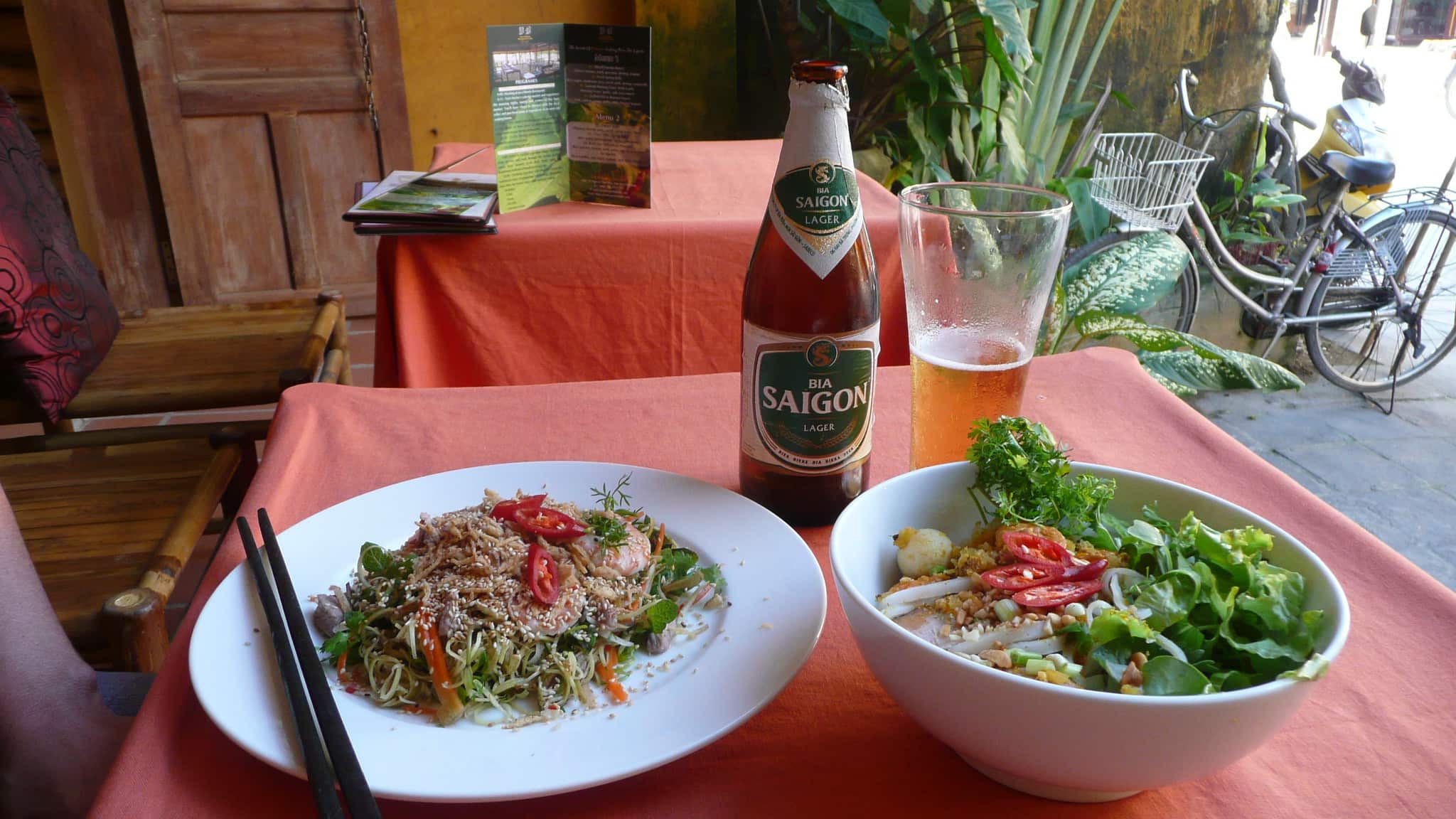 A photo of a lunch of banana flower salad and a bowl of beef pho accompanied by a cold Saigon beer in Hoi An Vietnam
